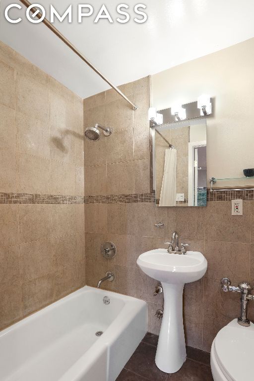 bathroom with toilet, tile walls, tile patterned floors, and shower / bath combo with shower curtain