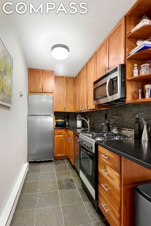 kitchen featuring decorative backsplash, a baseboard radiator, sink, and stainless steel appliances