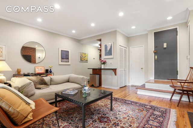 bedroom featuring light hardwood / wood-style floors, stainless steel built in fridge, a closet, and ornamental molding