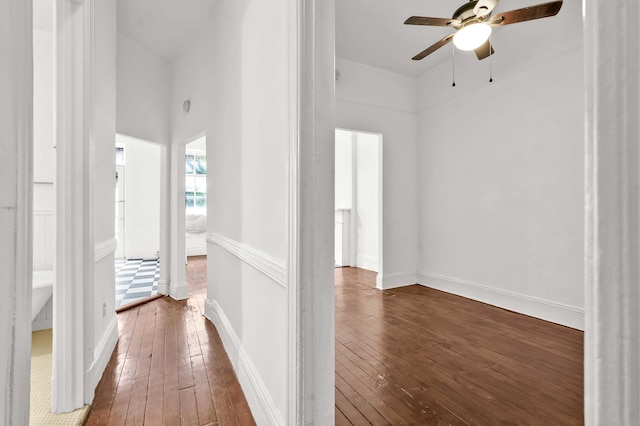 hallway with a towering ceiling, hardwood / wood-style flooring, and baseboards