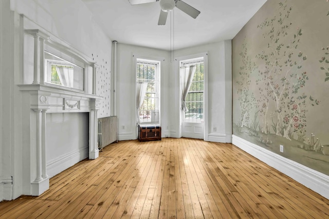 unfurnished living room featuring ceiling fan, a fireplace, baseboards, and hardwood / wood-style floors