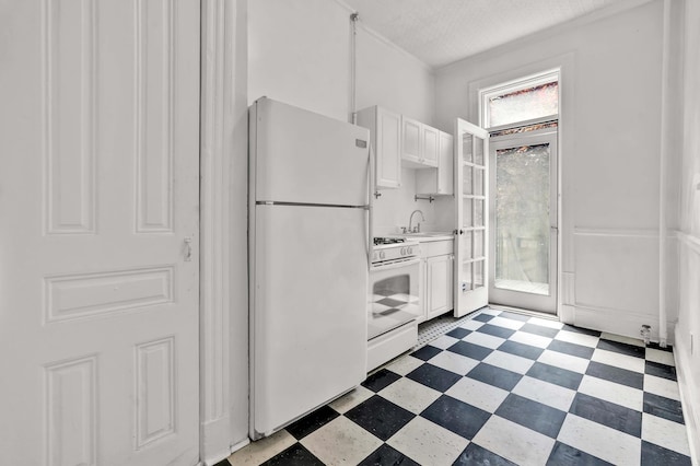 kitchen featuring white appliances, white cabinets, light countertops, light floors, and a sink