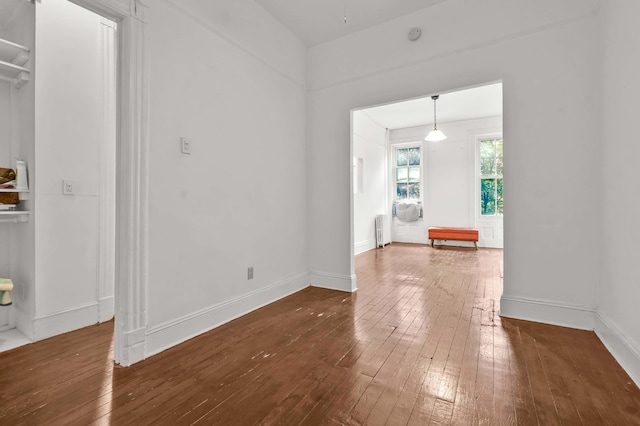 unfurnished dining area featuring radiator heating unit, dark wood finished floors, and baseboards