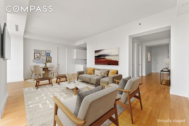 living area featuring baseboards, visible vents, and light wood-style floors