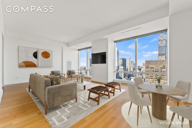 living area featuring floor to ceiling windows, baseboards, and light wood finished floors