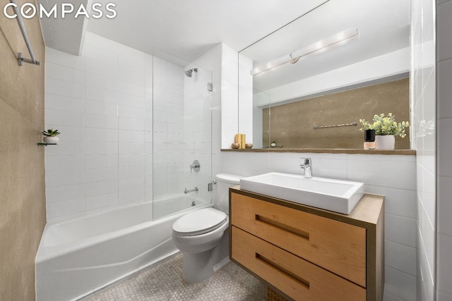 full bathroom with tiled shower / bath, tile patterned flooring, vanity, tile walls, and toilet