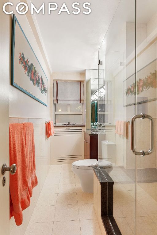 bathroom featuring toilet, tile patterned flooring, a shower with door, and vanity