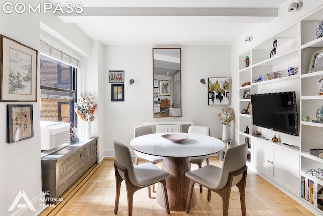 dining room with beam ceiling, a healthy amount of sunlight, cooling unit, and light parquet floors