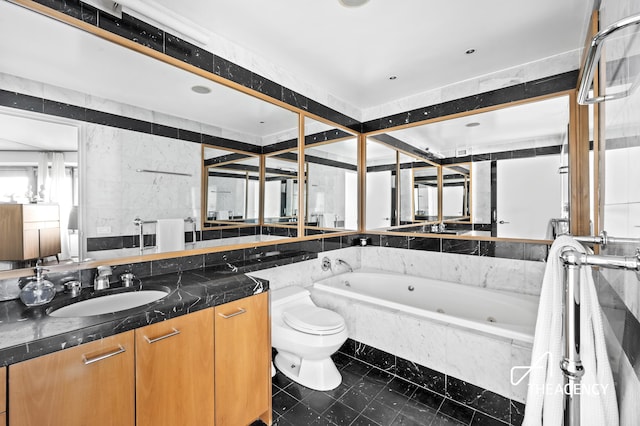 bathroom featuring a jetted tub, vanity, and toilet