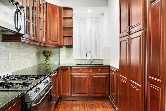 kitchen featuring reddish brown cabinets, range with gas cooktop, black microwave, and a sink