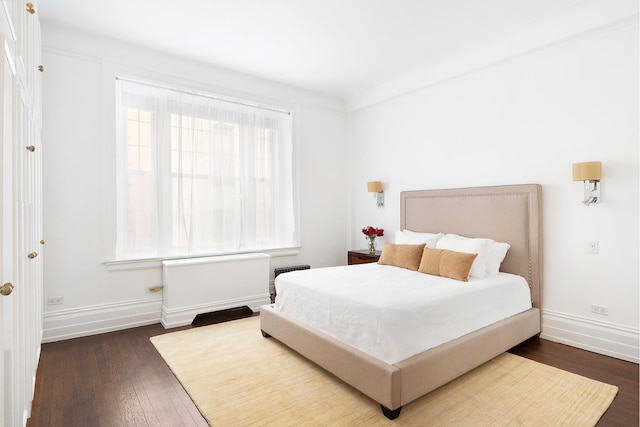 bedroom with radiator heating unit, dark wood-style flooring, and baseboards