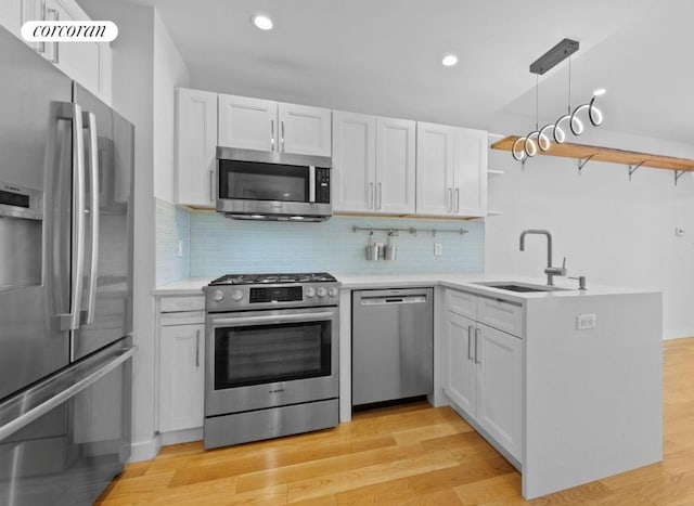 kitchen featuring pendant lighting, sink, appliances with stainless steel finishes, white cabinetry, and kitchen peninsula