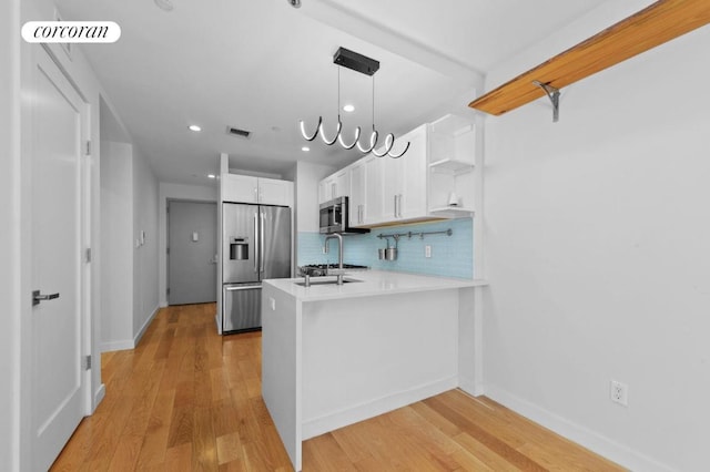 kitchen with white cabinetry, tasteful backsplash, hanging light fixtures, kitchen peninsula, and stainless steel appliances