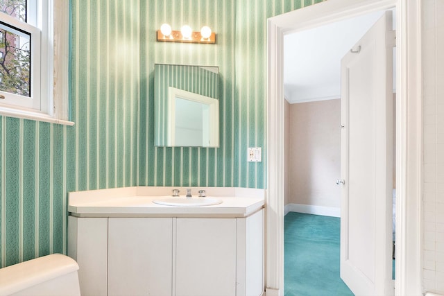 bathroom with baseboards, vanity, toilet, and wallpapered walls