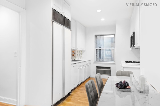 kitchen with white appliances, white cabinetry, light countertops, and recessed lighting