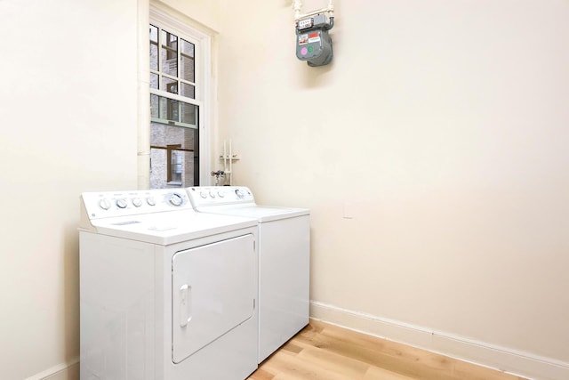 clothes washing area featuring washer and dryer, baseboards, and light wood-style floors