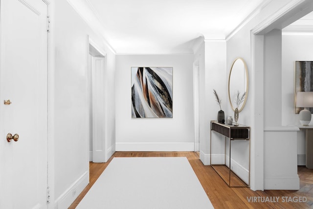 corridor with ornamental molding, wood finished floors, and baseboards