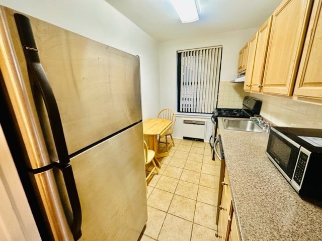 kitchen featuring backsplash, stainless steel refrigerator, sink, light brown cabinets, and light tile patterned floors