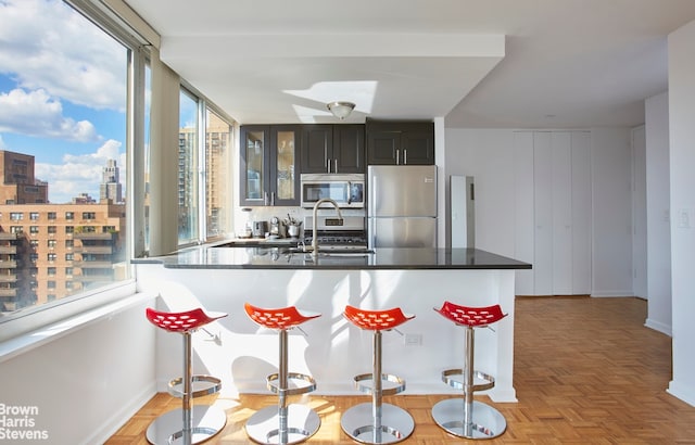 kitchen featuring appliances with stainless steel finishes, sink, a kitchen breakfast bar, kitchen peninsula, and light parquet floors