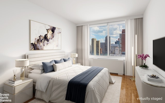 bedroom featuring radiator and light parquet flooring