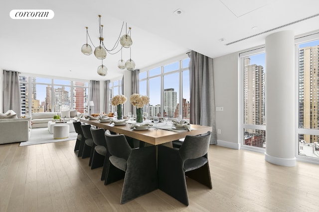 dining area with a wall of windows, a chandelier, and light hardwood / wood-style flooring