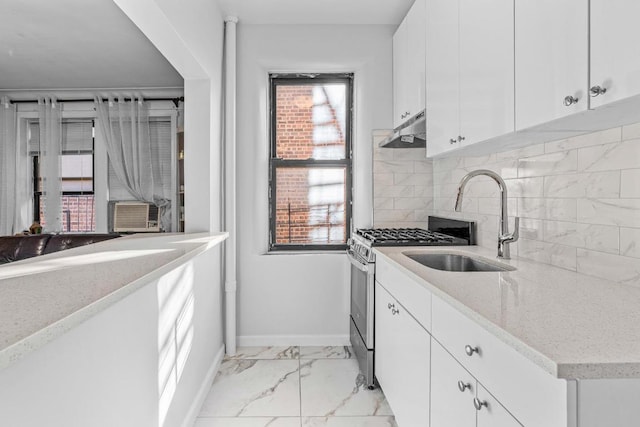 kitchen with backsplash, sink, stainless steel gas range, white cabinets, and light stone counters