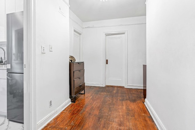 hallway featuring dark wood-type flooring and baseboards