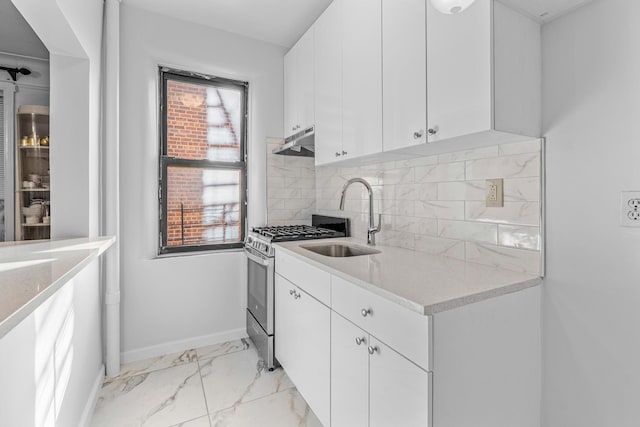 kitchen featuring under cabinet range hood, a sink, marble finish floor, stainless steel gas stove, and tasteful backsplash