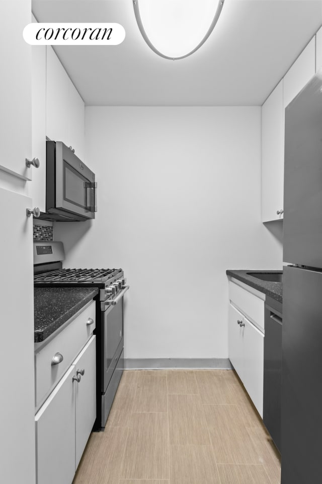 kitchen with appliances with stainless steel finishes, white cabinets, and dark stone counters