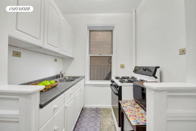 kitchen with sink, white cabinetry, and gas range oven