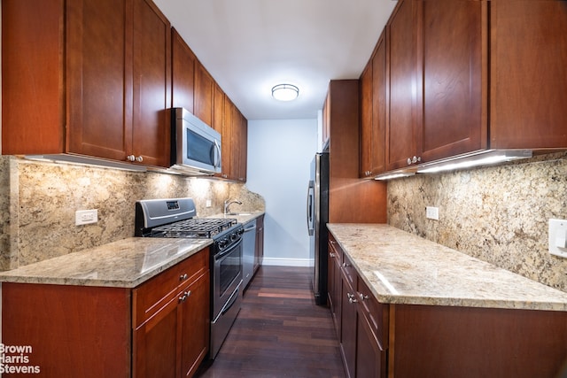 kitchen featuring stainless steel appliances, decorative backsplash, dark hardwood / wood-style floors, light stone counters, and sink