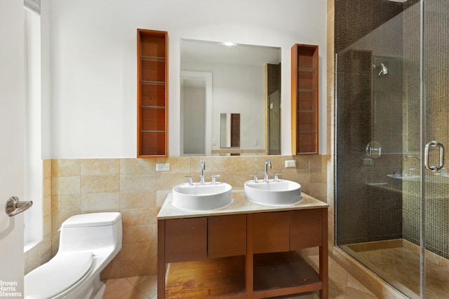 bathroom with toilet, a stall shower, tile walls, and a sink