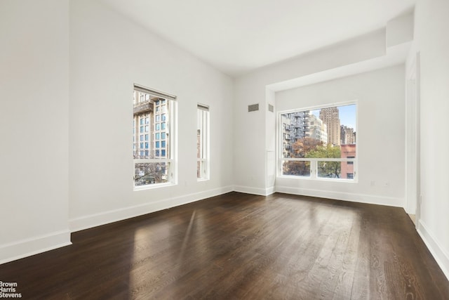 empty room with baseboards, a city view, and dark wood-type flooring