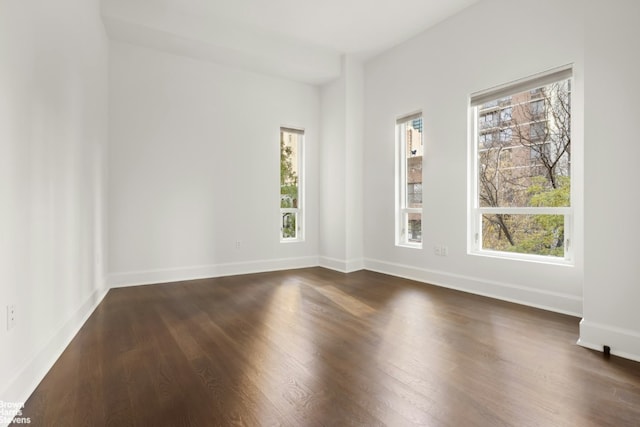 unfurnished room with dark wood-style floors and baseboards