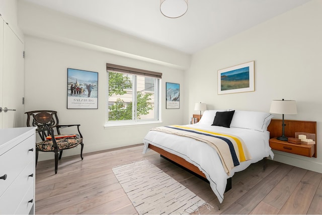 bedroom featuring light wood finished floors and baseboards