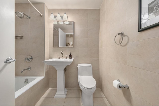 bathroom with toilet, tile patterned flooring, tile walls, and tiled shower / bath