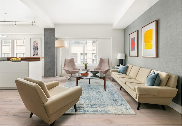 living room featuring rail lighting, an accent wall, wood finished floors, and wallpapered walls