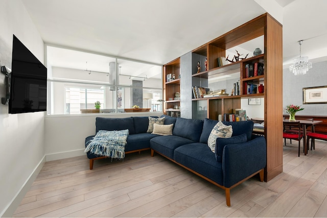 living room with a chandelier, light wood-style flooring, and baseboards