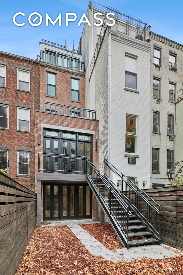 rear view of property with brick siding and stairs