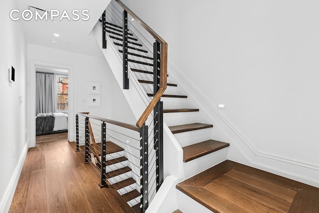 staircase featuring baseboards and wood finished floors