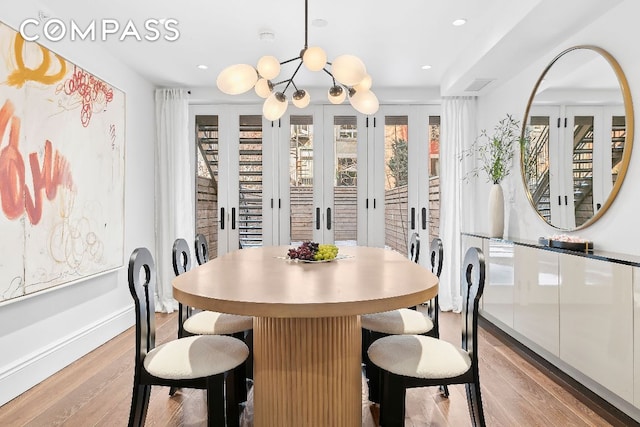 dining area with light hardwood / wood-style floors, french doors, and a chandelier