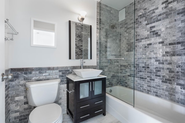 22 W 15th St Unit 7I, New York City, NY 10011 - bathroom with bath / shower combo with glass door, toilet, tile walls, vanity, and a wainscoted wall