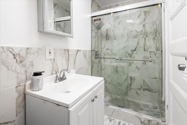 full bath with a marble finish shower, vanity, and tile walls