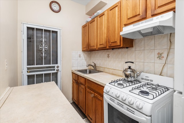 kitchen with under cabinet range hood, a sink, light countertops, white gas range oven, and backsplash