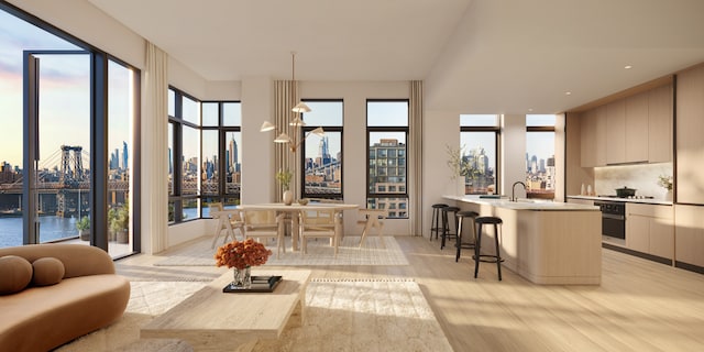 interior space with wall oven, an island with sink, a water view, light countertops, and light wood-style floors