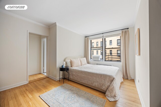 bedroom with hardwood / wood-style floors, ornamental molding, and radiator