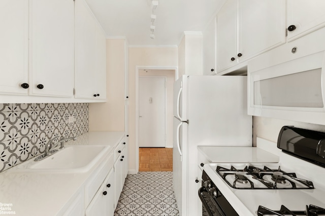 kitchen with white appliances, a sink, white cabinets, light countertops, and ornamental molding