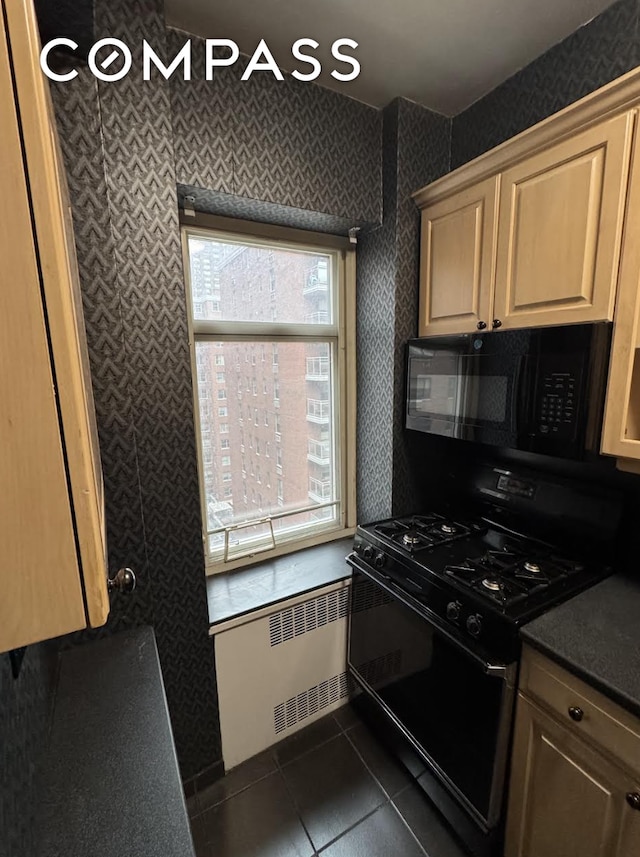 36 Sutton Pl S Unit 8E, New York City, NY 10022 - kitchen with black appliances, radiator, dark tile patterned floors, dark countertops, and wallpapered walls