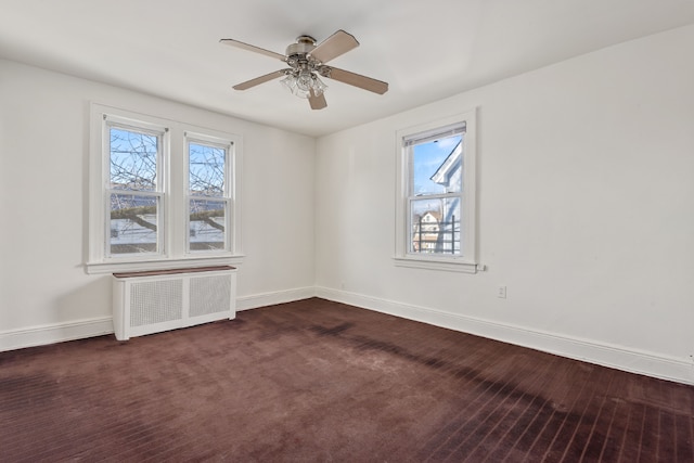 carpeted empty room featuring ceiling fan, a healthy amount of sunlight, and radiator