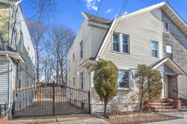 view of home's exterior with entry steps, fence, and a gate